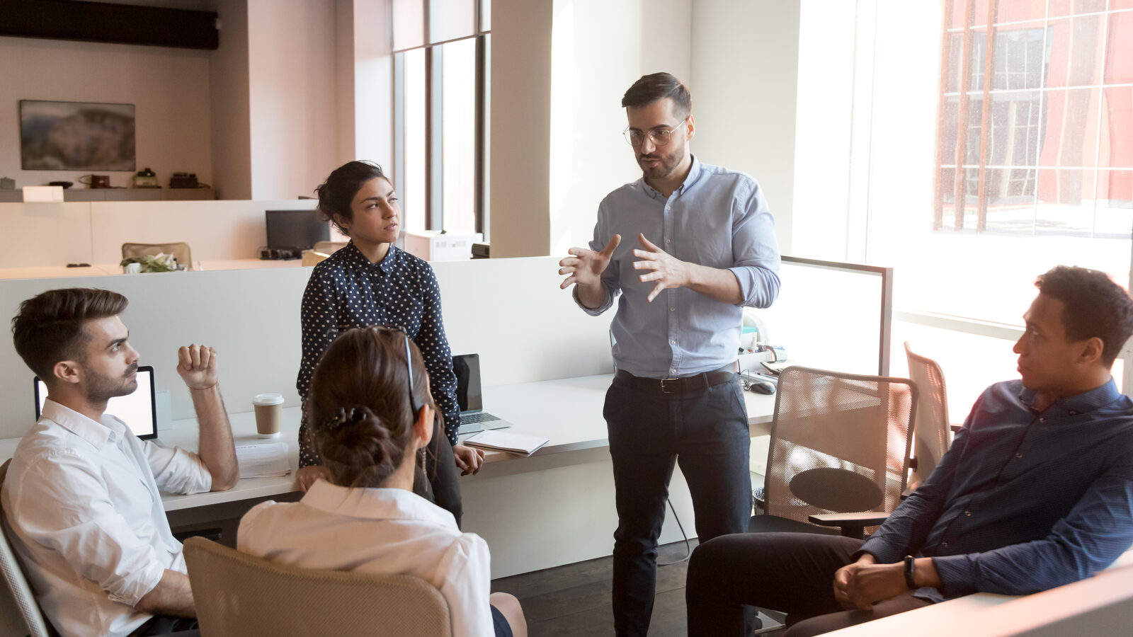 Consultant leading a team meeting in an open office